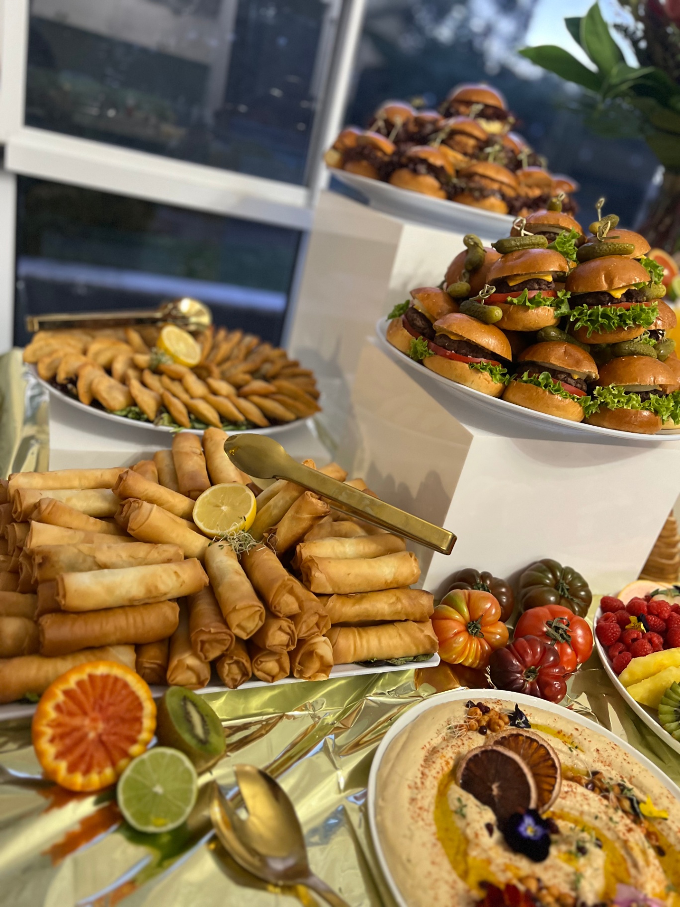 Tiered display of sliders, spring rolls and hummus