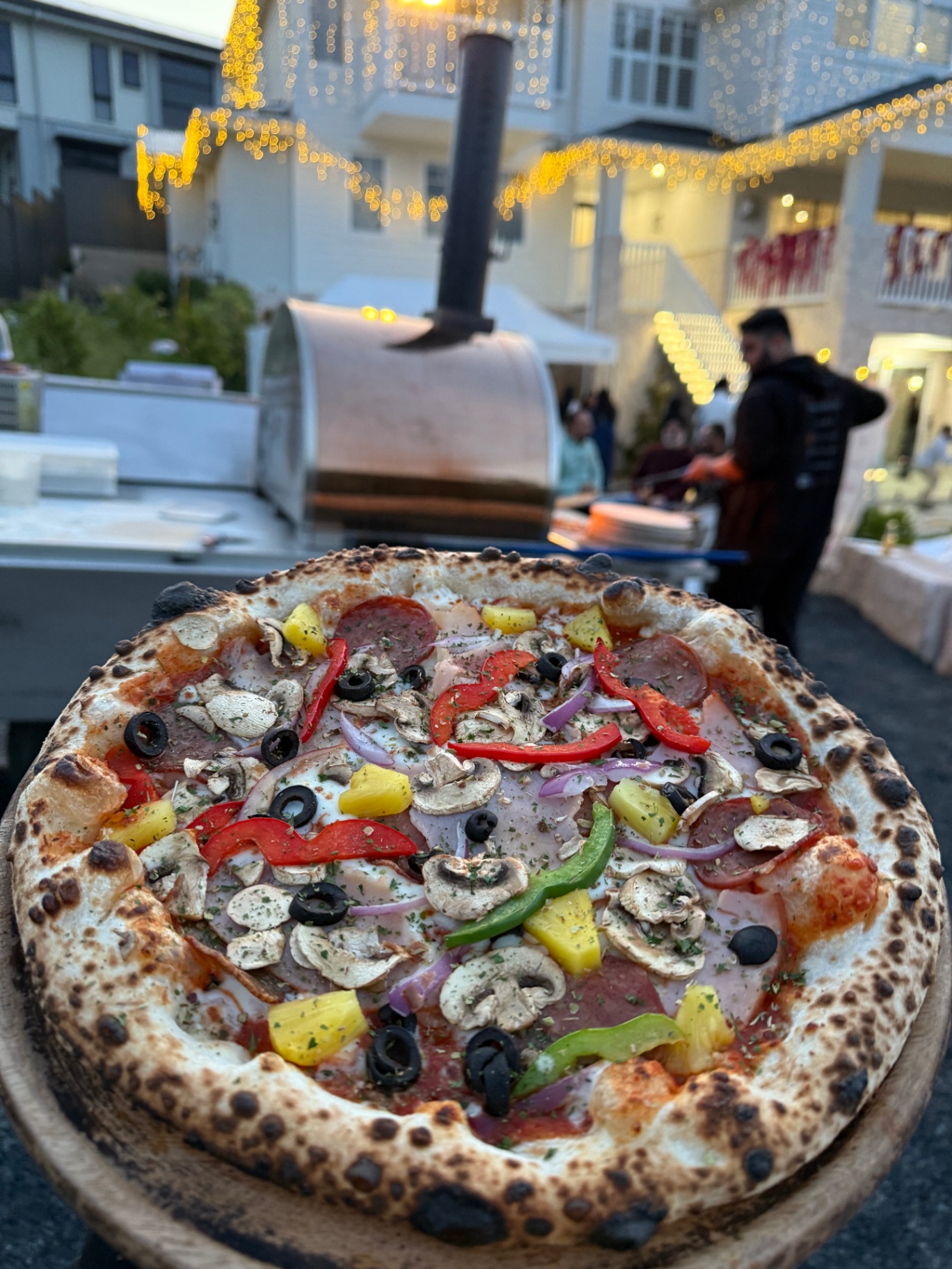 Supreme pizza served at a nighttime event with glowing lights